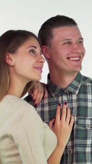 Joyful couple embracing, gazing dreamily into the distance