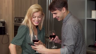 A joyful couple, holding of red wine, captures a selfie in their stylish new apartment, celebrating love on Valentine's Day. The warm