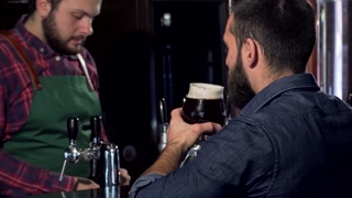 Unrecognizable man savoring a rich craft beer at a lively pub