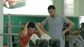 Fitness trainer guiding a young man in abdominal exercises
