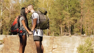 Young couple of hikers kisses near the cliff