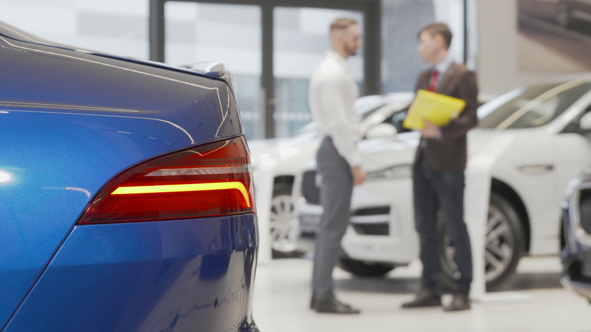 Car dealer shaking hands with male client at automobile dealership