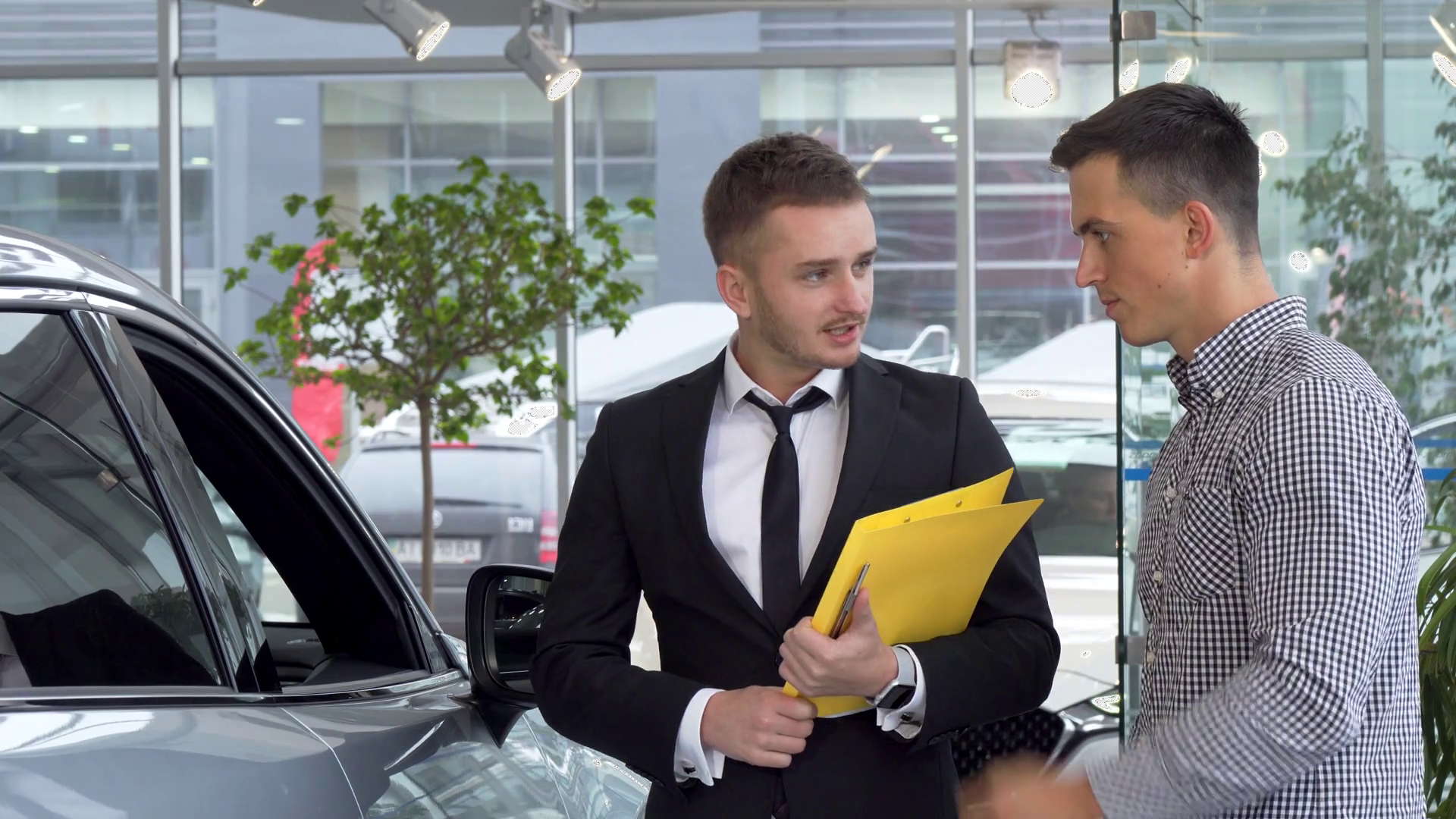 Friendly car dealer helping his male customer choosing automobile to buy Stock Video Footage 00