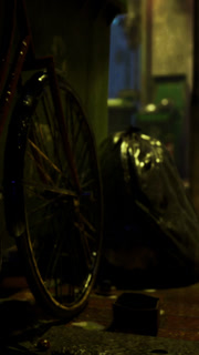 Rainy night scene with bicycle and trash bag in an alleyway shrouded in mystery