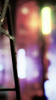 Ladder stands in focus with colorful background lights at a venue