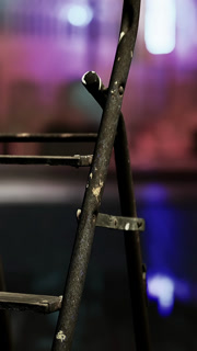 Ladder stands in focus with colorful background lights at a venue