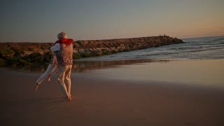 Elderly couple embracing on the beach at sunset