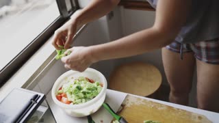 Woman preparing salad in home kitchen