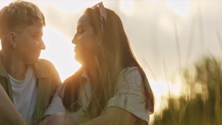 Young lesbian couple enjoying intimacy in a field at sunset