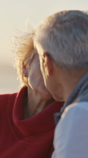 Elderly couple kissing on beach at sunset