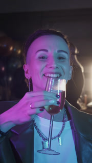 A portrait of beautiful adult woman with shaved temples drinks alcohol and eats snacks at a corporate party