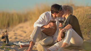 Romantic mature couple kissing during beach picnic