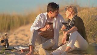 Romantic senior couple kissing during beach picnic