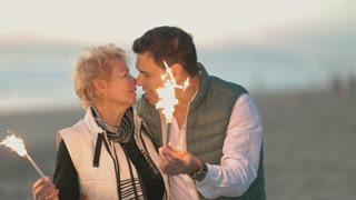 Romantic senior couple kissing with sparklers on a beach