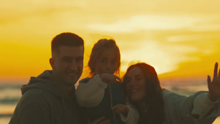 Family waves goodbye at sunset on beach while enjoying time together in summer