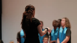 Female choir conductor leading singers on stage