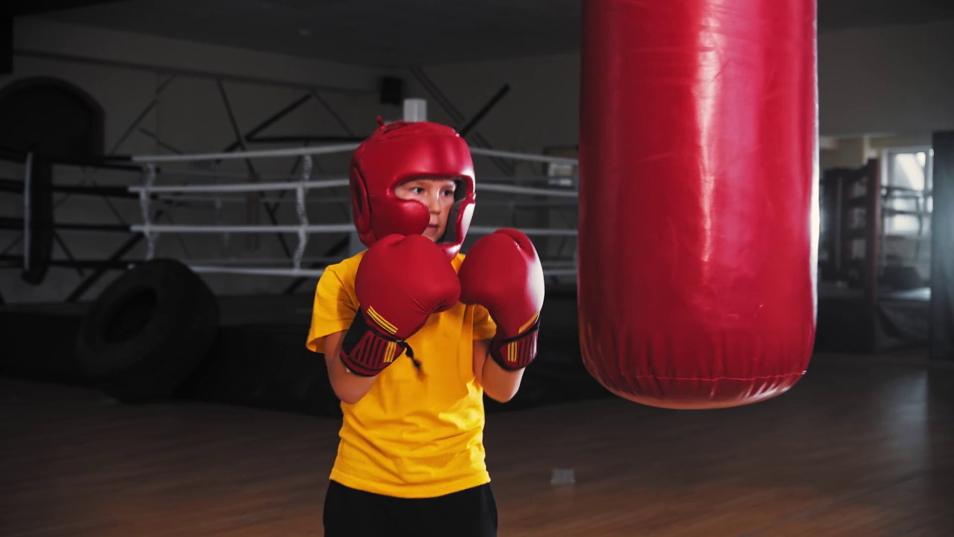 Little boy boxer hitting a big punching bag on training then falls on