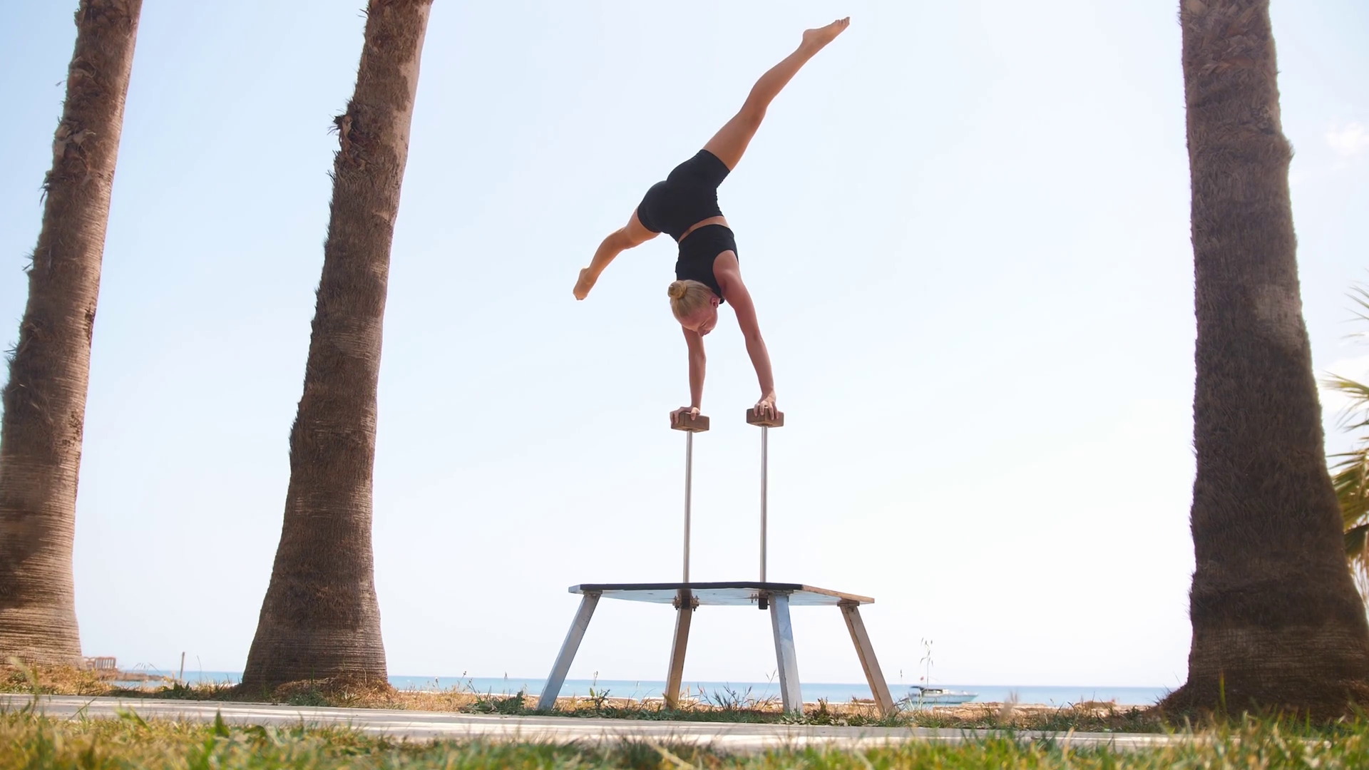A young gymnastic woman standing on the high beams with her hands and