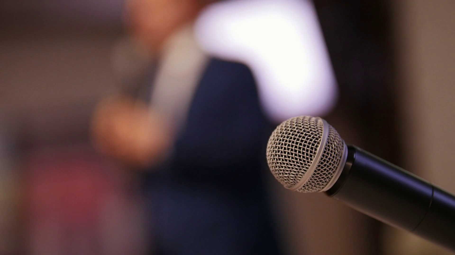 A business conference in the hall. A man talking on the stage. A mic on