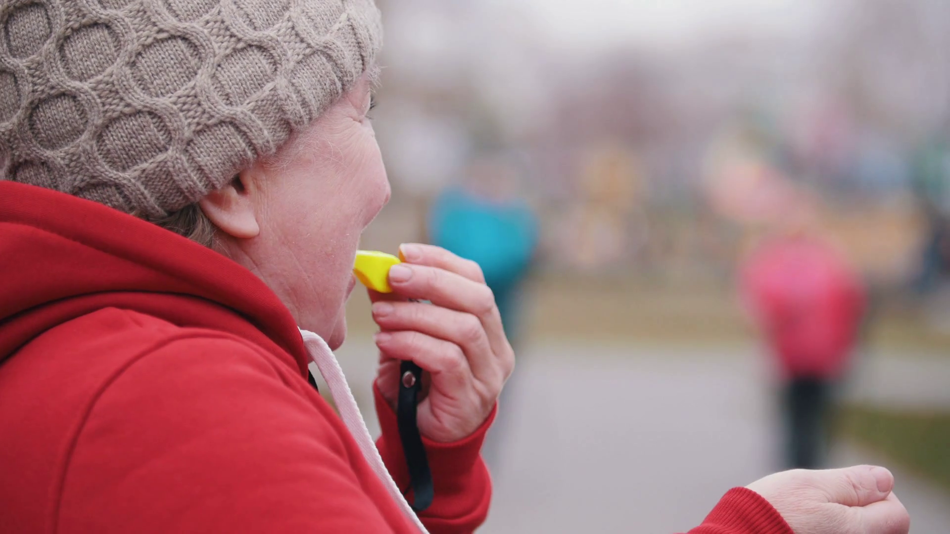 An old woman blows on whistle amd two elderly women starts walking on