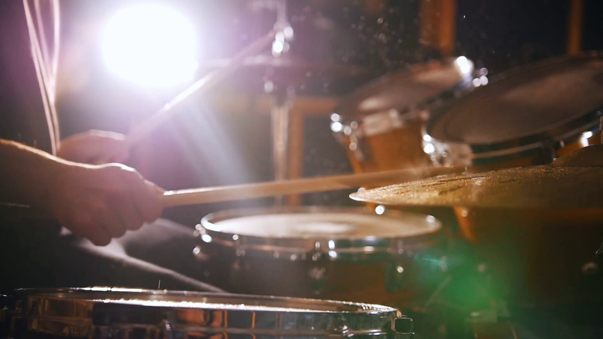 Drummer plays music on wet drums in studio in a garage. Close up Stock