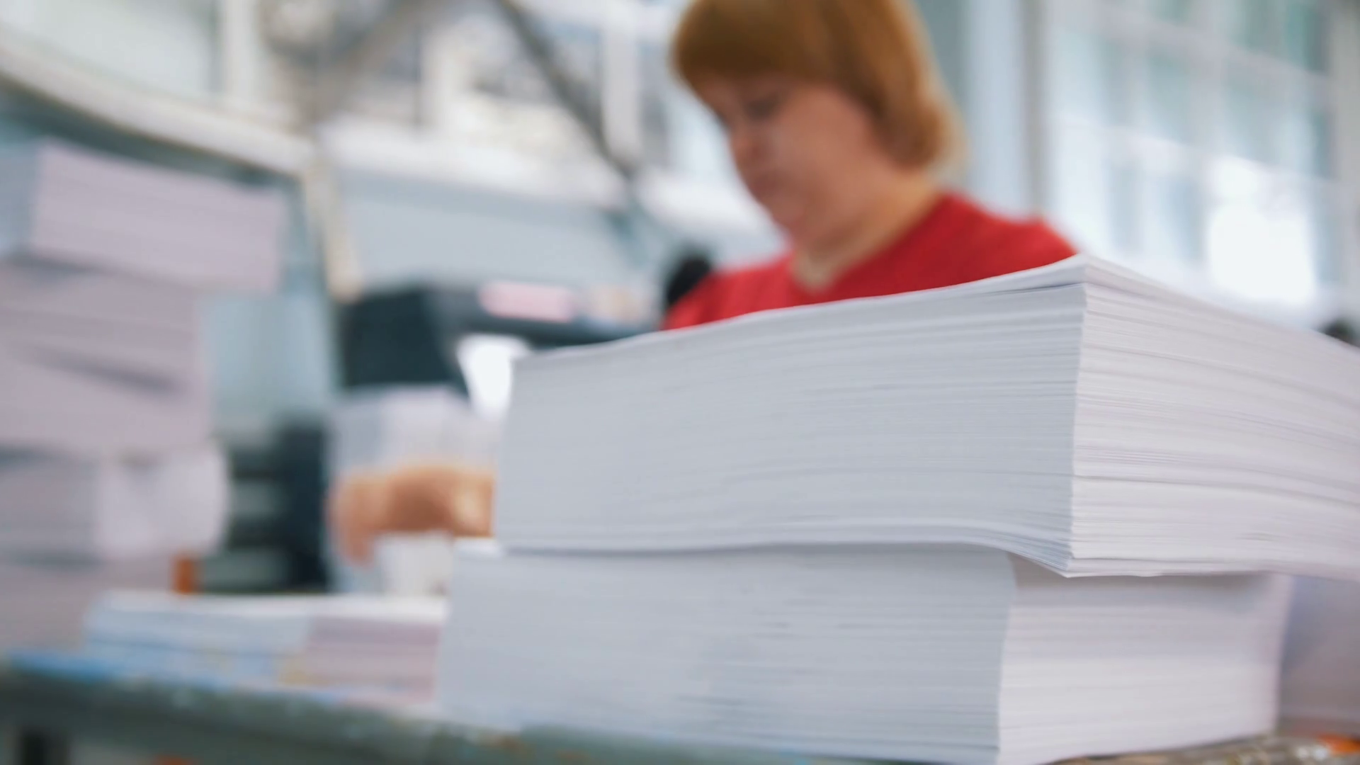 Paper stack in front of female worker sorting a papers in the