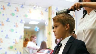 Stylist styles and grooms young boy's hair