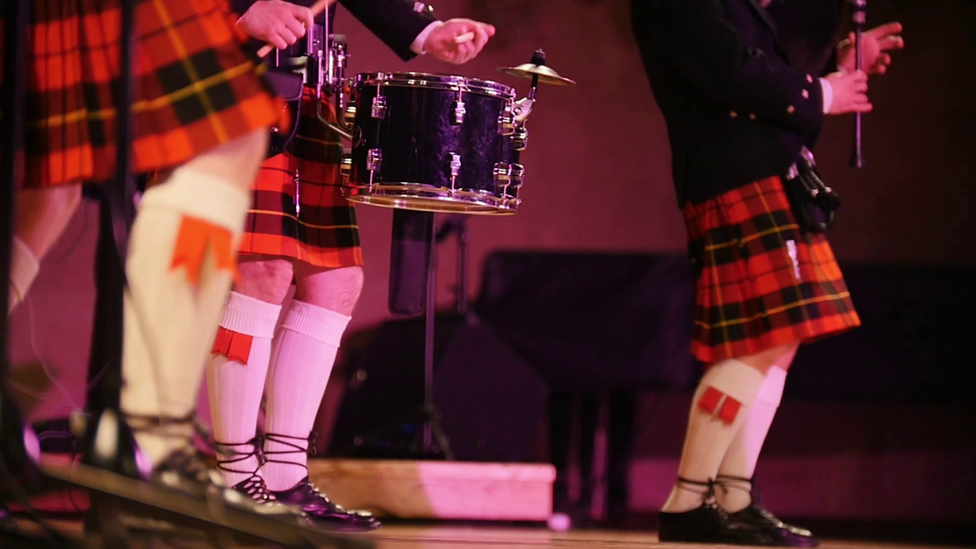 Traditional scottish band musicians in white socks and kilts singing
