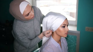 Two muslim women to tie Islamic turban, preparing for a wedding