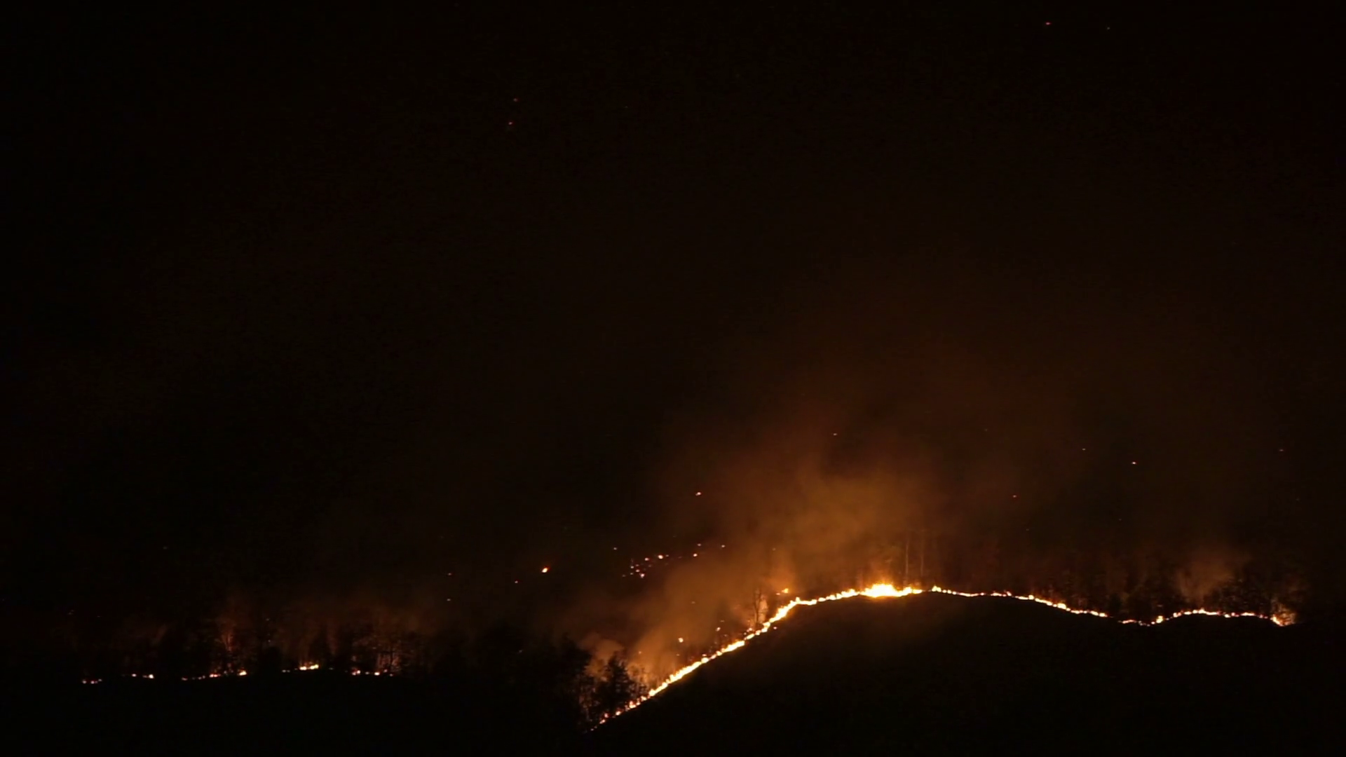 Forest fire over the mountain top line at night. Conflagration disaster