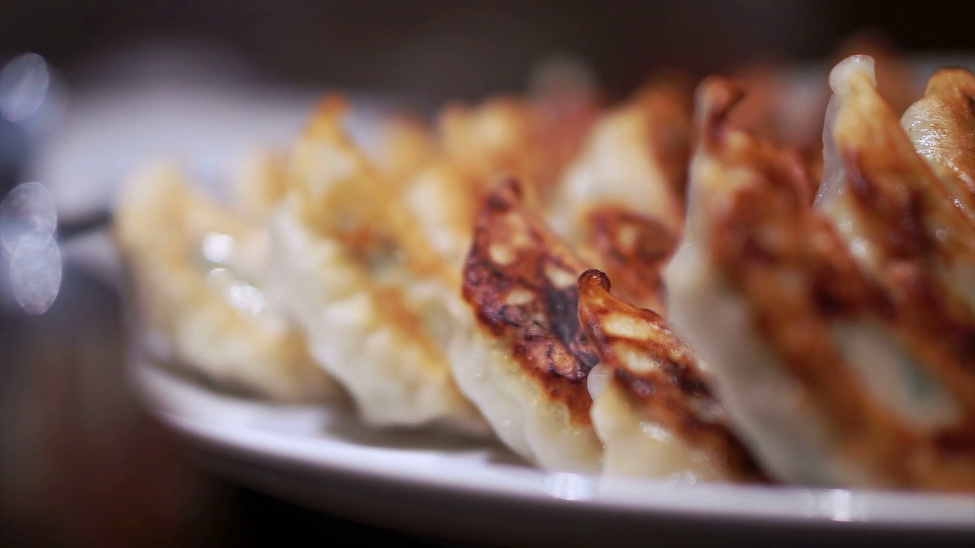 Plate full of delicious Japanese gyoza with one side burnt crust. Eating by chopsticks Stock