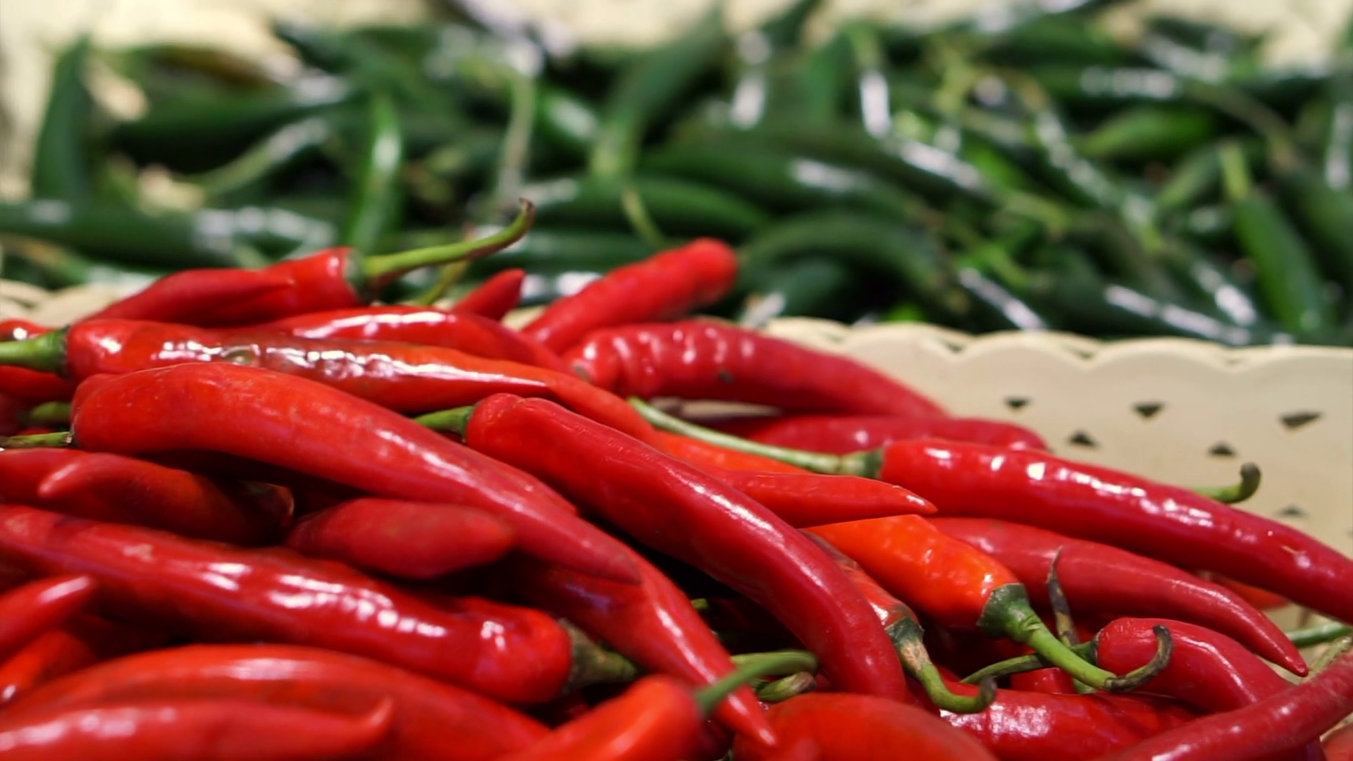 Red and green chili peppers selling in supermarket different basket