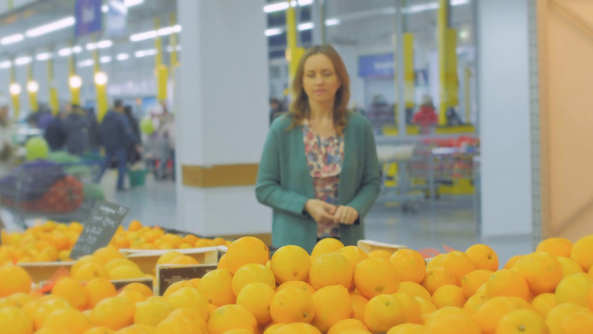 Woman selecting fresh oranges in grocery store produce department and