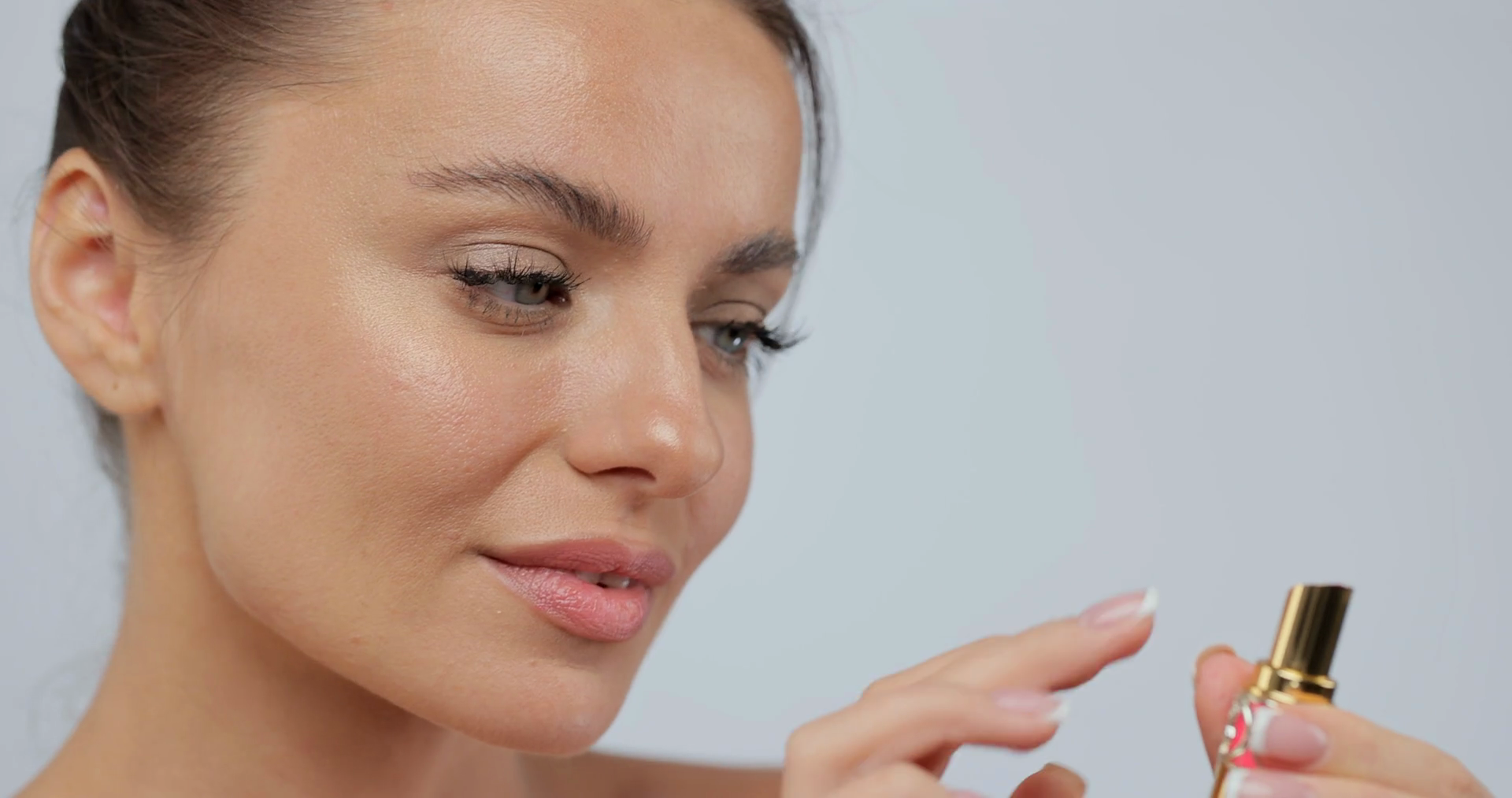 Close up woman applying lipstick smiling to camera making makeup posing