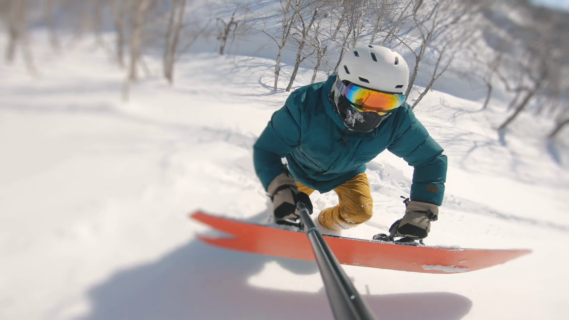 Person filming himself with selfie stick climbing up slope with help of