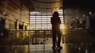 Silhouette of man and woman meeting in airport terminal after arrival. Happy couple kissing, man whirling his girlfriend. Concept of travel. Sunset panoramic window at background. 6k downscale 10 bit