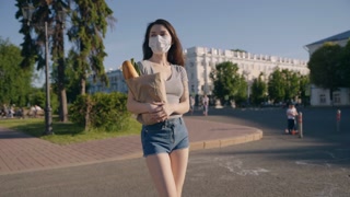 Woman in protective gear carries bag from store to home. Pandemic shopping. Social distancing for prevention. Life after quarantine. Covid effect concept.