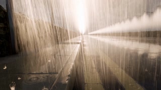 Raindrops bouncing off the surface of a rain-soaked sidewalk and road surface.