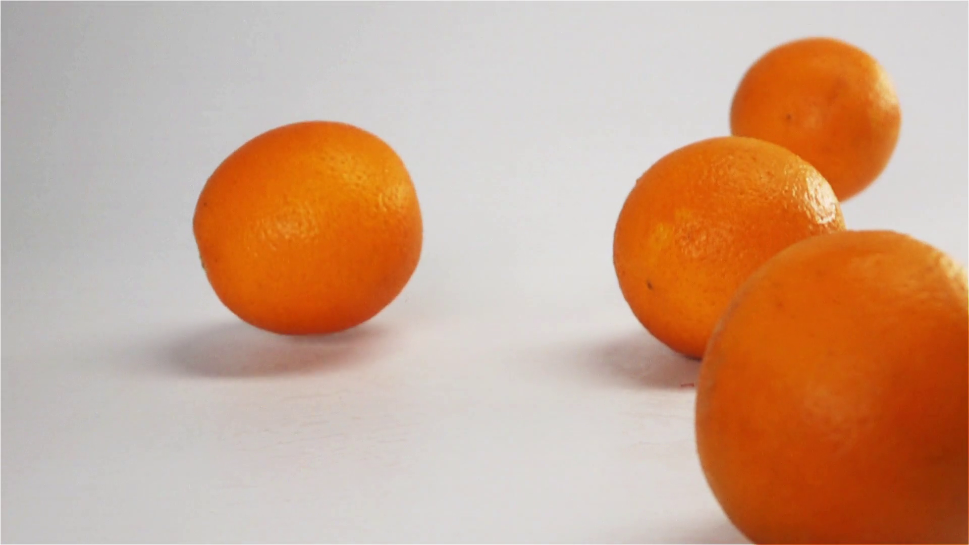 Oranges falling and bouncing on white wet surface in slow motion Stock