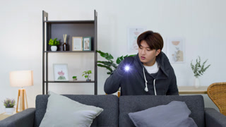 Burglar in Dark Hoodie Searching Living Room with Flashlight at Night