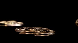 Golden Cryptocurrency Tokens Dropping Onto Reflective Black Surface