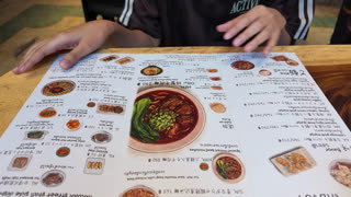 Asian Woman Pointing at Taiwanese Food Menu in Bangkok Restaurant