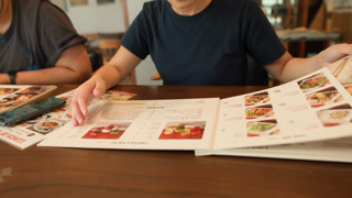Choosing Dishes From Restaurant Menu at Dining Table
