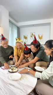 Asian Family Cutting Birthday Cake Together at Home