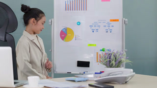Young Asian Girl in Suit Presenting Business Data on Whiteboard