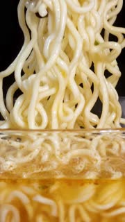 Chopsticks Lifting Instant Noodles from Hot Broth Bowl