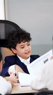 Young Asian Boy in Suit Leading Business Meeting in Modern Office