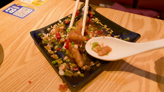 Chopsticks Placing Spicy Chicken Feet Dim Sum onto Ceramic Spoon