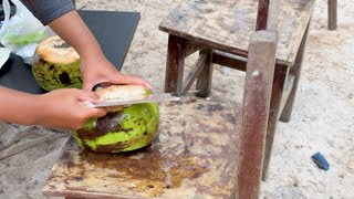 Street Food Vendor Cutting Fresh Green Coconut with Large Cleaver
