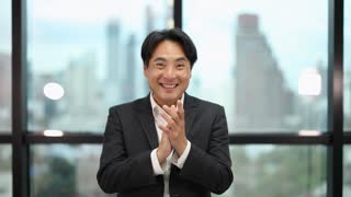 Confident Asian Businessman Clapping and Smiling in Modern Office